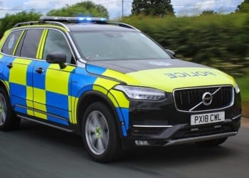 A Cumbria police Volvo 4x4 pictured side on travelling along a road with blue flashing lights
