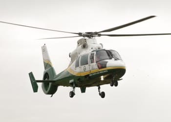 A Great North Air Ambulance helicopter flying in the sky. It is white, yellow and green