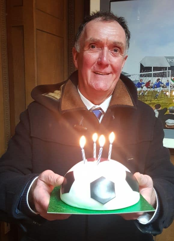 Dave Atkinson holding football shaped birthday cake