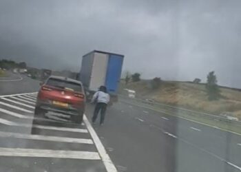 Dramatic video footage shows a motorist parking his vehicle on the M6 and cheating death by walking within inches of passing cars and lorries
