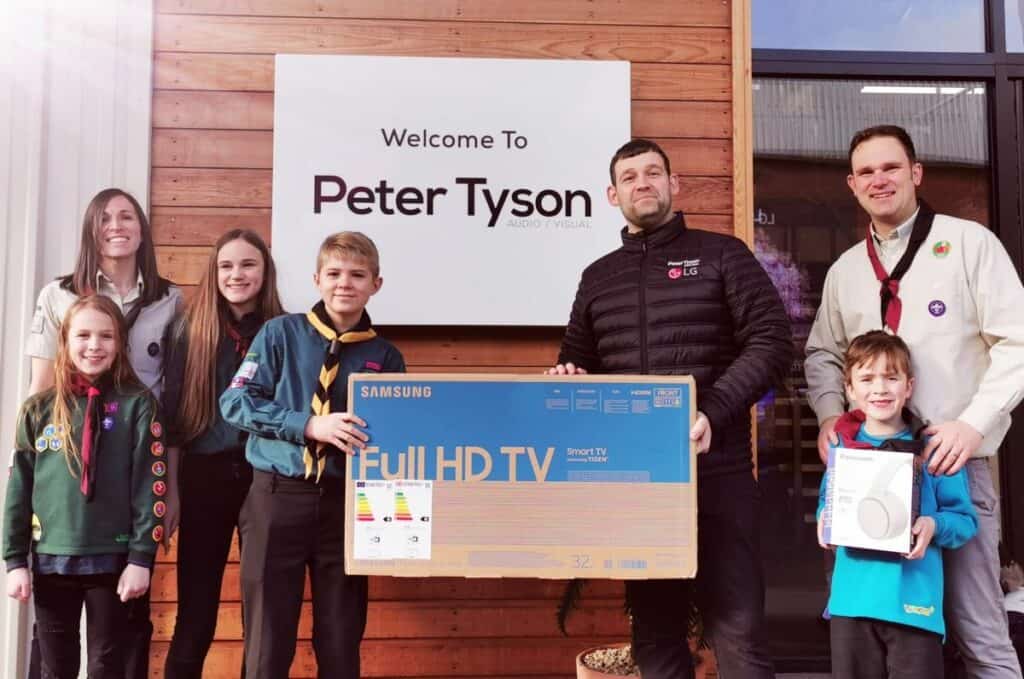 Peter Tyson hand over a TV to support a Cumbria Scouts raffle. Peter Tyson representative poses with Cumbria Scouts