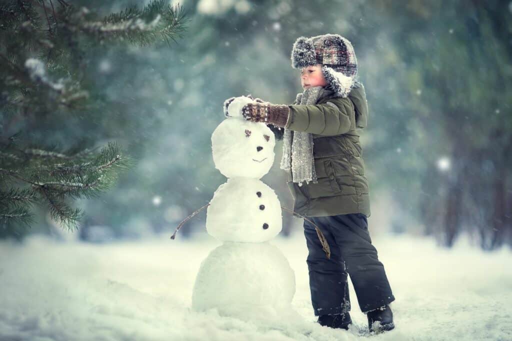 child building snowman in a forest