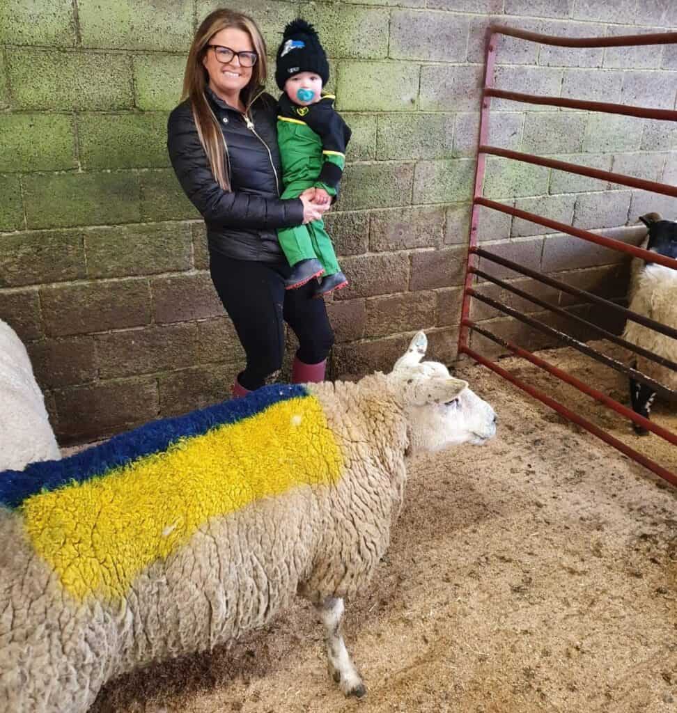 Rachel Wood with Junior and their sheep. The sheep is painted in the blue and yellow of Ukraine