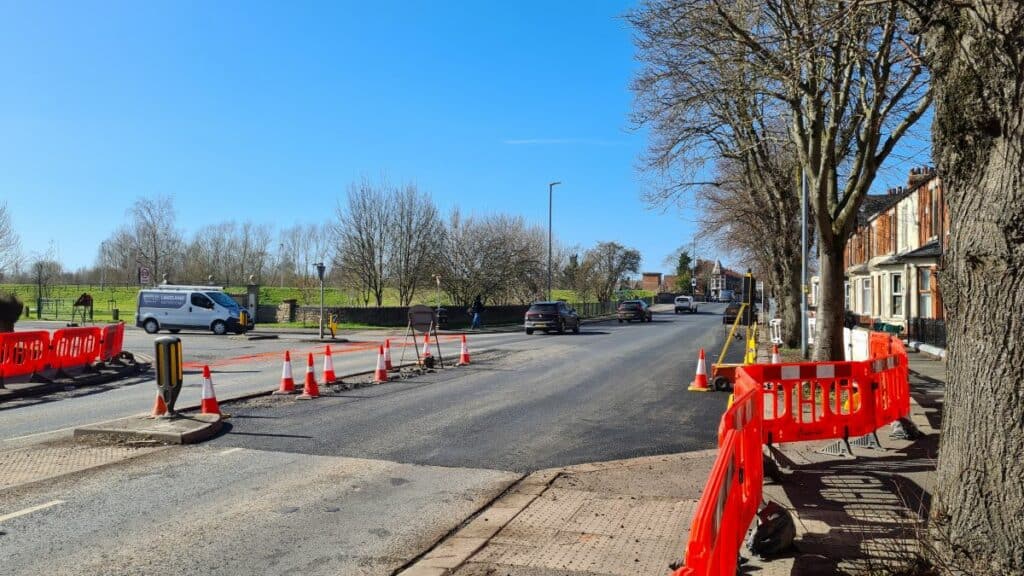 Part of Warwick Road has been resurfaced but has not yet been painted with road markings. Orange barriers are blocking the crossing outside the Premier Inn and block the edge of the road from the pavement