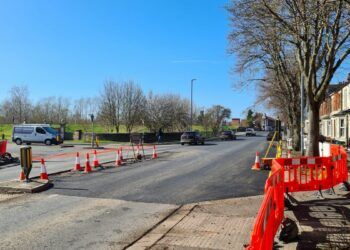 Part of Warwick Road has been resurfaced but has not yet been painted with road markings. Orange barriers are blocking the crossing outside the Premier Inn and block the edge of the road from the pavement