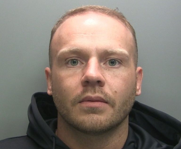 Kane Hull is pictured against a grey background and is wearing a black hoodie