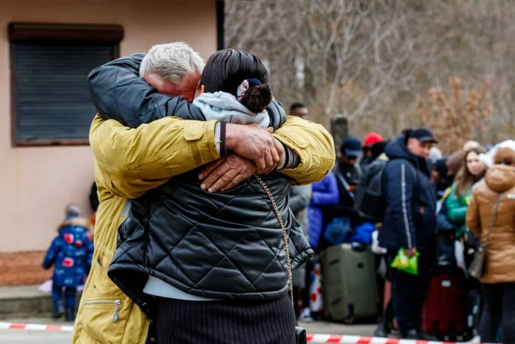 A man says goodbye to his wife who is fleeing Russian aggression. In the background are Refugees on the Ukrainian-Slovak border.