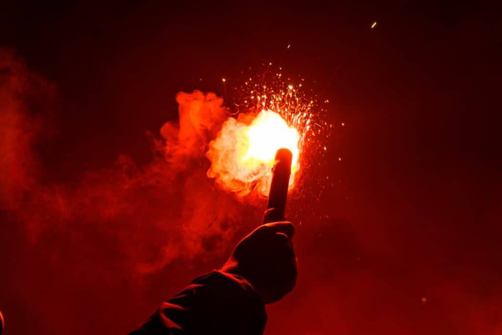 A man holds a flare used at football matches aloft