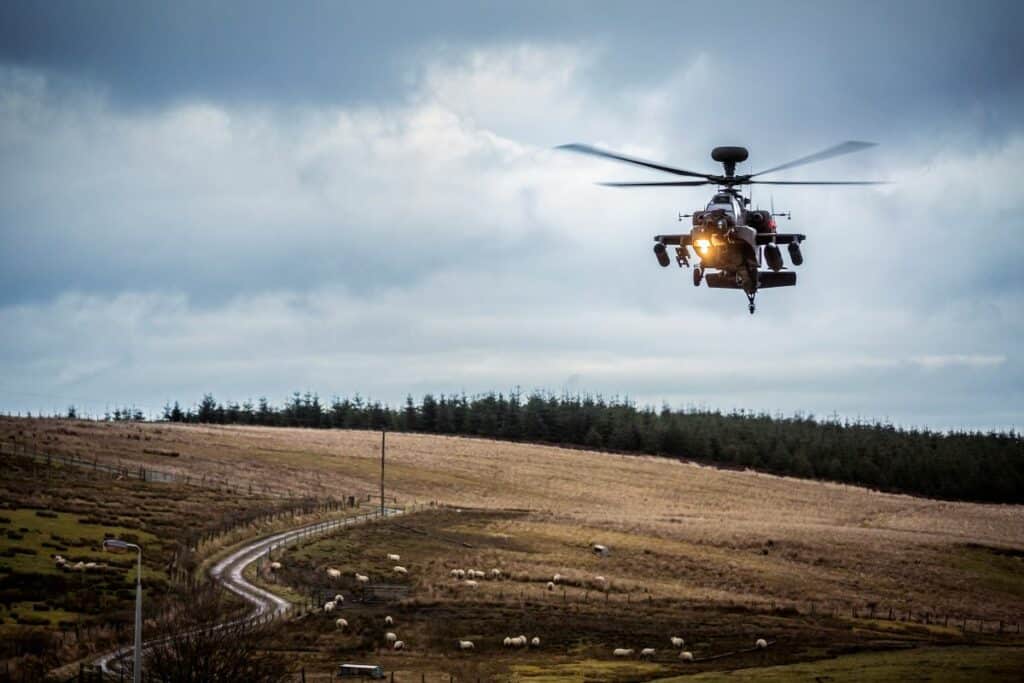 A helicopter flies in RAF Spadeadam with greys skies behind it