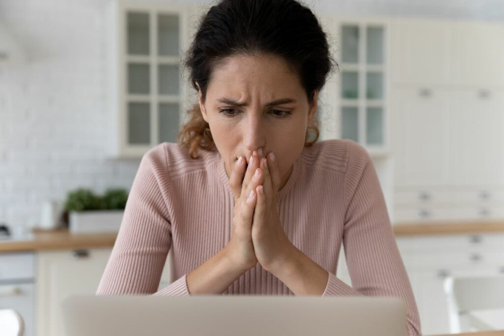 Woman looking worried while looking at laptop