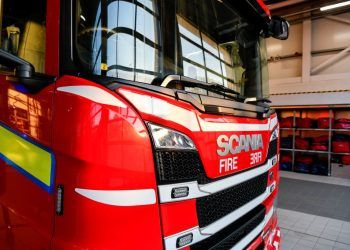 A close-up of a red fire engine with white and yellow markings parked in a fire station.